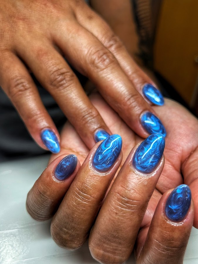 Deep metallic blue chrome almond nails with a celestial marbled finish